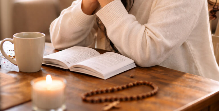 a woman praying with a devotional booklet