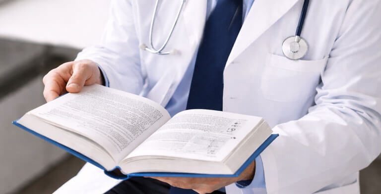 A doctor reading a hardcover medical journal book